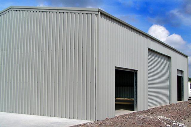 A grey building with a large closed roller door in-between two smaller open roller doors
